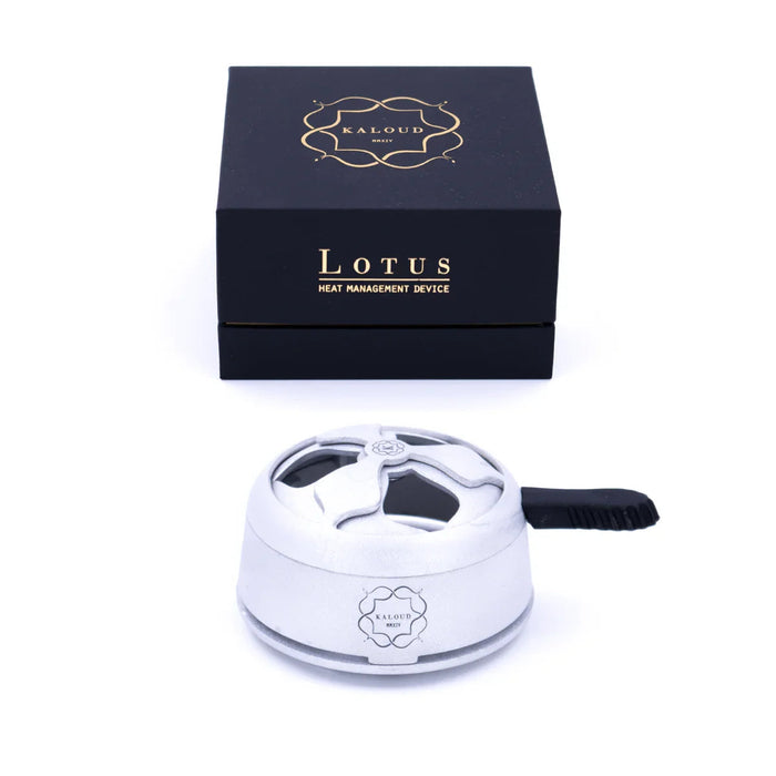 Kaloud Lotus heat management device in light silver with a black handle and flower-shaped openings, in front of the black box reading Lotus.